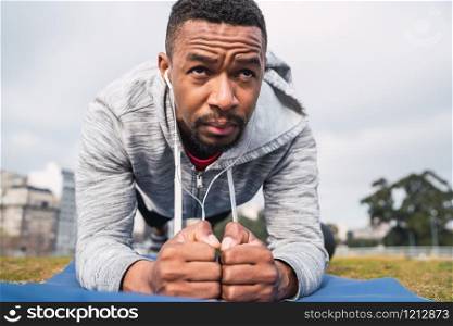 Portrait of an athletic man doing exercise at the park outdoors. Sport and healthy lifestyle concept.
