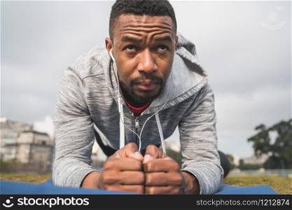 Portrait of an athletic man doing exercise at the park outdoors. Sport and healthy lifestyle concept.