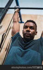 Portrait of an athletic man doing pull up exercise at the gym. Sport and healthy lifestyle concept.