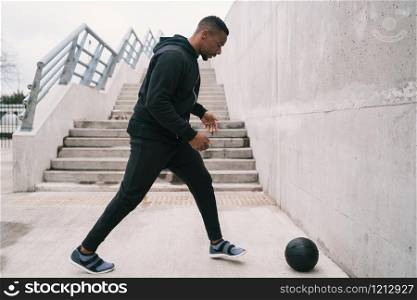 Portrait of an athletic man doing wall ball exercise outdoors. Sport and healthy concept.
