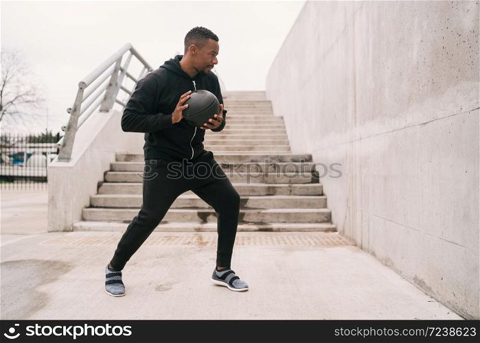 Portrait of an athletic man doing wall ball exercise outdoors. Sport and healthy concept.