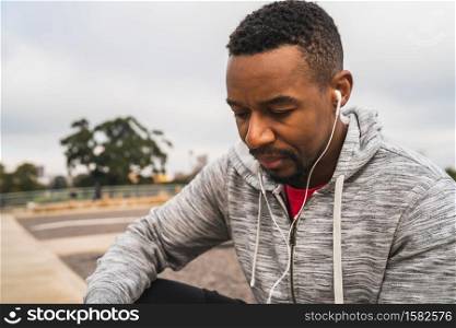 Portrait of an athletic man listening to music with earphones while resting for exercise. Sport and healthy lifestyle.