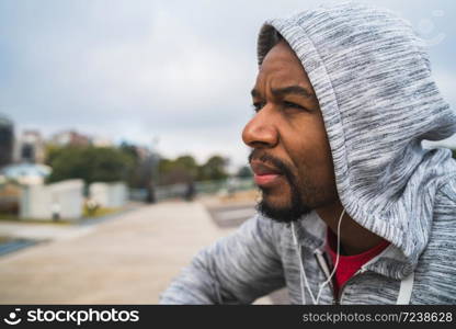 Portrait of an athletic man listening to music with earphones while resting for exercise. Sport and healthy lifestyle.