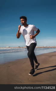 Portrait of an athletic man running at the beach. Sport, fitness and healthy lifestyle.