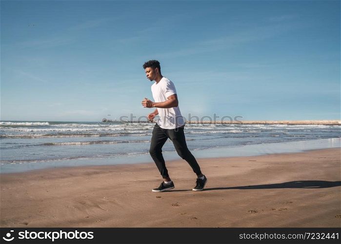 Portrait of an athletic man running at the beach. Sport, fitness and healthy lifestyle.