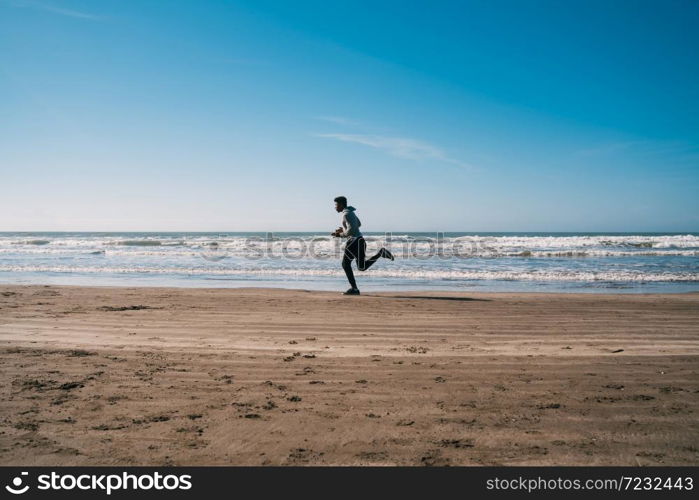 Portrait of an athletic man running at the beach. Sport, fitness and healthy lifestyle.