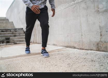 Portrait of an athletic man running on the street against grey background. Sport and healthy lifestyle.