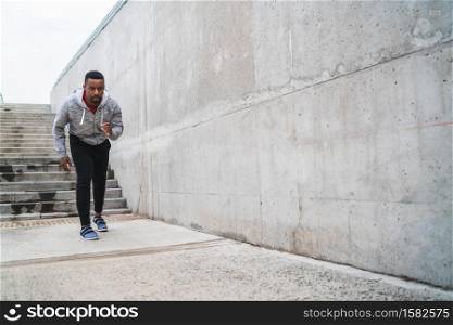 Portrait of an athletic man running on the street against grey background. Sport and healthy lifestyle.