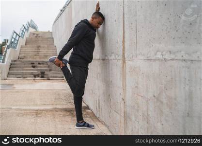 Portrait of an athletic man stretching legs before exercise outdoors. Sport and healthy lifestyle.