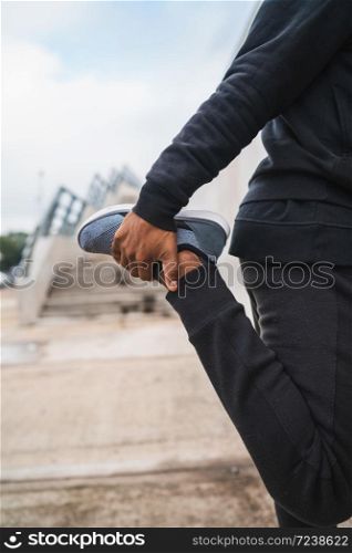 Portrait of an athletic man stretching legs before exercise outdoors. Sport and healthy lifestyle.