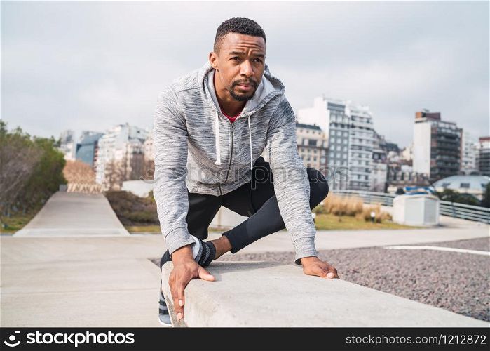 Portrait of an athletic man stretching muscles before exercise outdoors. Sport and healthy lifestyle.