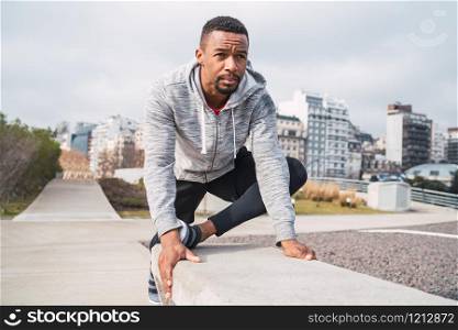 Portrait of an athletic man stretching muscles before exercise outdoors. Sport and healthy lifestyle.