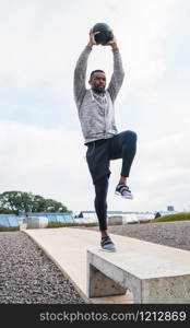 Portrait of an athletic man training with medicine ball at the park outdoors. Sport and healthy concept.