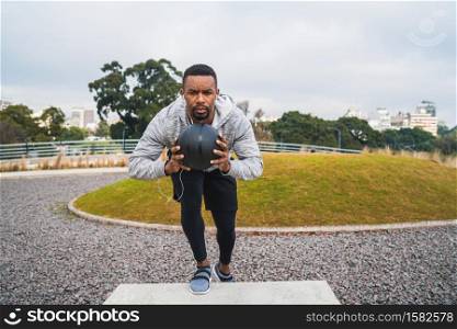 Portrait of an athletic man training with medicine ball at the park outdoors. Sport and healthy concept.