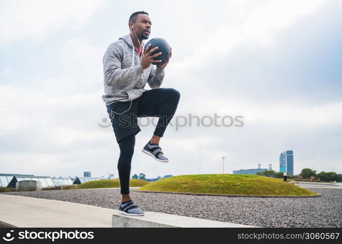 Portrait of an athletic man training with medicine ball at the park outdoors. Sport and healthy concept.