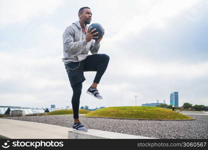 Portrait of an athletic man training with medicine ball at the park outdoors. Sport and healthy concept.