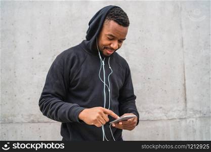 Portrait of an athletic man using his mobile phone on a break from training against grey background. Sport and health lifestyle.