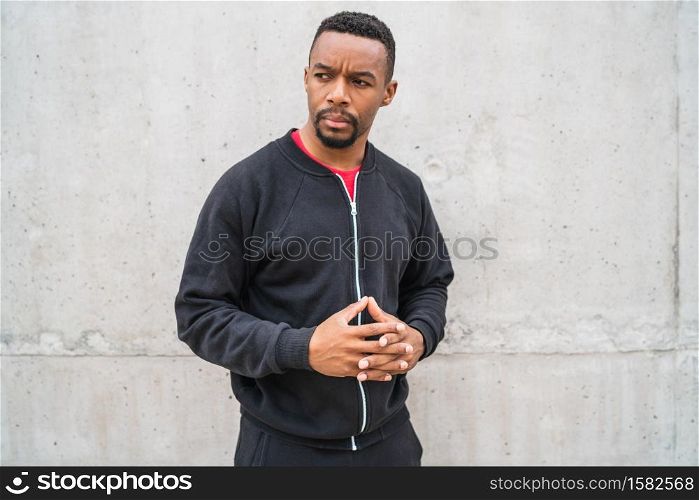 Portrait of an athletic man wearing sport clothes against grey background. Sport and healthy lifestyle.