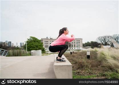 Portrait of an athletic woman doing exercise at the park outdoors. Sport and healthy lifestyle concept.