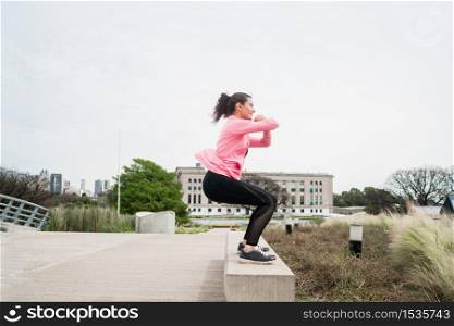 Portrait of an athletic woman doing exercise at the park outdoors. Sport and healthy lifestyle concept.