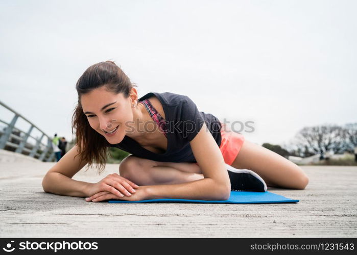Portrait of an athletic woman doing exercise with yoga mat. Sport and healthy lifestyle concept.