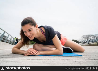 Portrait of an athletic woman doing exercise with yoga mat. Sport and healthy lifestyle concept.