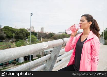 Portrait of an athletic woman drinking water after training. Sport and health lifestyle concept.