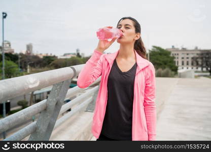 Portrait of an athletic woman drinking water after training. Sport and health lifestyle concept.