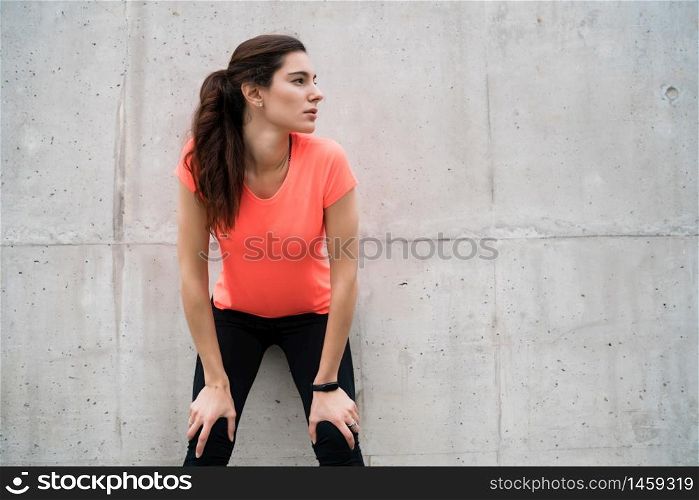 Portrait of an athletic woman on break from training against grey background. Sport and health lifestyle.