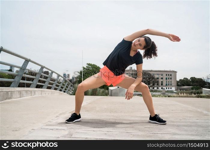 Portrait of an athletic woman stretching before exercise outdoors. Sport and healthy lifestyle.