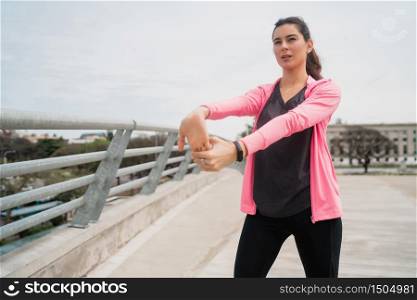 Portrait of an athletic woman stretching her arms before exercise outdoors. Sport and healthy lifestyle.