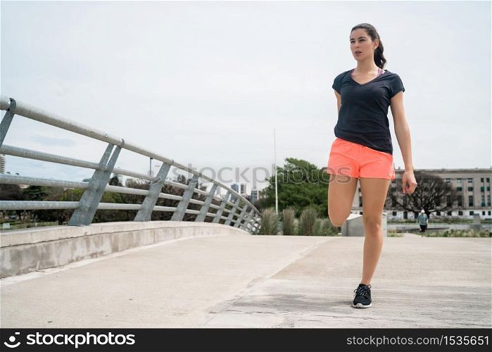 Portrait of an athletic woman stretching her arms before exercise outdoors. Sport and healthy lifestyle.