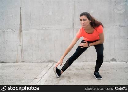 Portrait of an athletic woman stretching legs before exercise outdoors. Sport and healthy lifestyle.