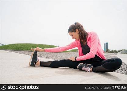 Portrait of an athletic woman stretching legs before exercise outdoors. Sport and healthy lifestyle.