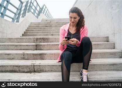 Portrait of an athletic woman using her mobile phone on a break from training. Sport and health lifestyle.