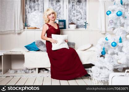 Portrait of an attractive blonde girl in a red dress. Christmas background.