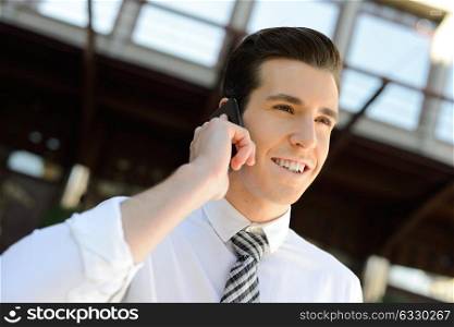 Portrait of an attractive businessman making a call using a smart phone in an office building