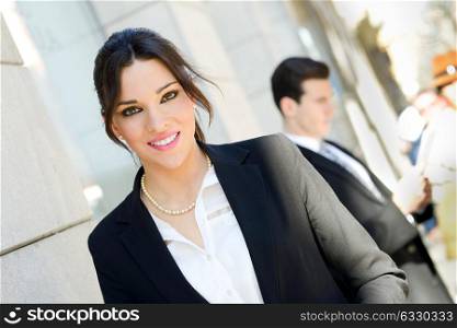 Portrait of an attractive businesswoman standing outside of company building. Couple working.