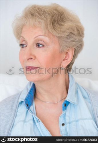 Portrait of an attractive elegant senior woman relaxingand dreaming at home