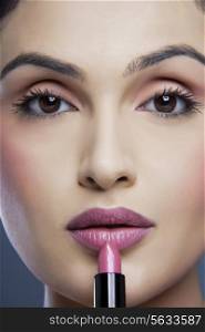 Portrait of an attractive female applying lipstick