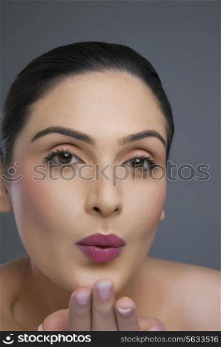 Portrait of an attractive female blowing kiss over colored background