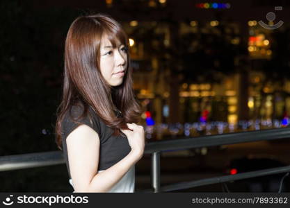 Portrait of an attractive Japanese tourist woman smiling and visiting a shopping mall in the city of Taipei lights in the background.