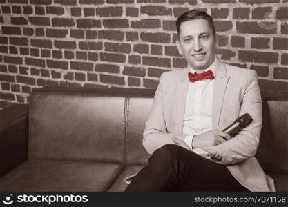 portrait of an attractive man in a suit against a brick wall with a microphone