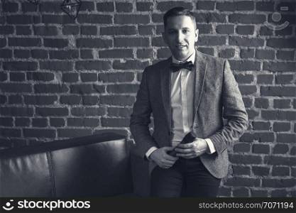 portrait of an attractive man with a microphone in his hands and in a suit against a brick wall
