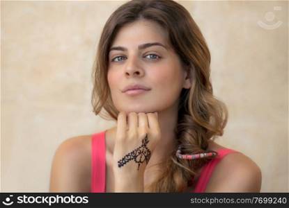 Portrait of an Attractive Woman Isolated on Beige Background with Beautiful Henna Drawing on the Hand. Stylish Body Art. Authentic Beauty of Young Female.