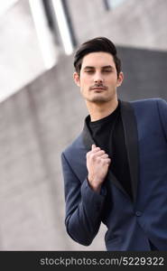 Portrait of an attractive young businessman outdoors, wearing modern suit.