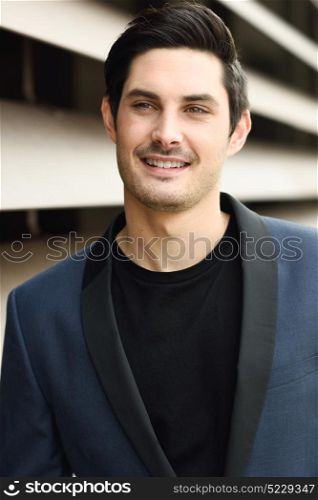 Portrait of an attractive young businessman outdoors, wearing modern suit.