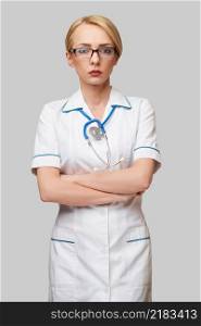Portrait of an attractive young female doctor nurse in white coat over light grey background.. Portrait of an attractive young female doctor nurse in white coat over light grey background