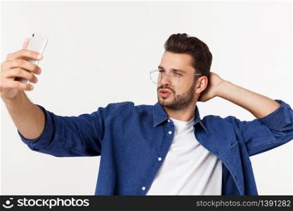 Portrait of an attractive young man taking a selfie while standing and pointing finger isolated over white background. Portrait of an attractive young man taking a selfie while standing and pointing finger isolated over white background.