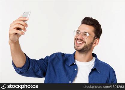 Portrait of an attractive young man taking a selfie while standing and pointing finger isolated over white background. Portrait of an attractive young man taking a selfie while standing and pointing finger isolated over white background.